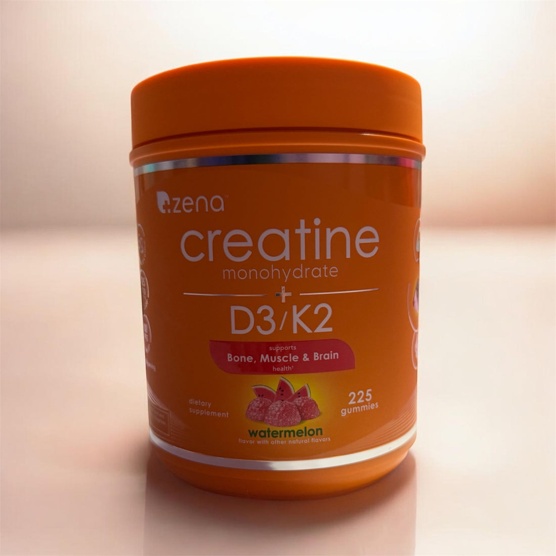 Orange container of Zena Creatine Monohydrate + D3/K2 gummies on a light background
