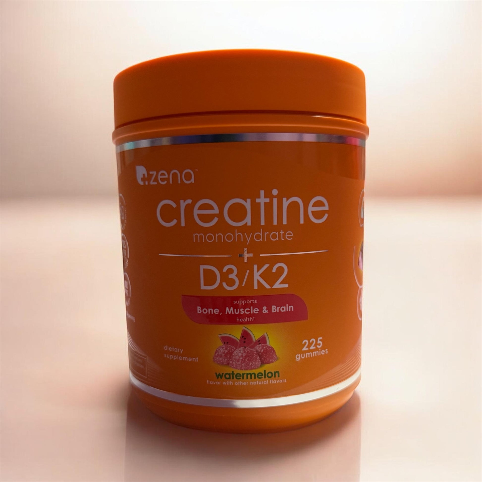 Orange container of Zena Creatine Monohydrate + D3/K2 gummies on a light background