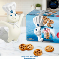 Wilton cookie dough mascot with a box of chocolate chip cookies and packaging on a kitchen counter.